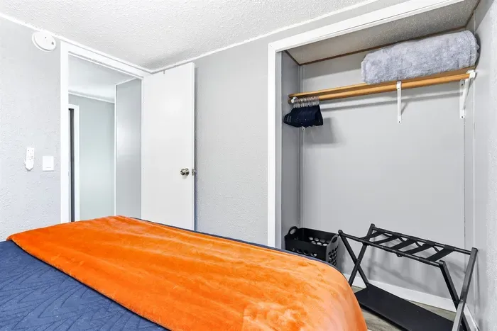 Modern bedroom with an airy open closet and comfortable bed.