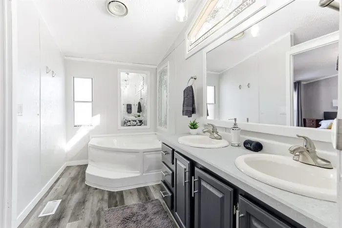 Spacious bathroom with a relaxing soaking tub, double vanity, and plenty of natural light. Clean, modern finishes create a calm, spa-like feel, perfect for getting ready or unwinding.