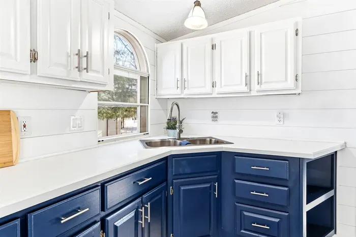 Modern kitchen featuring sleek blue lower cabinets and crisp white upper cabinets, fully equipped for effortless cooking.