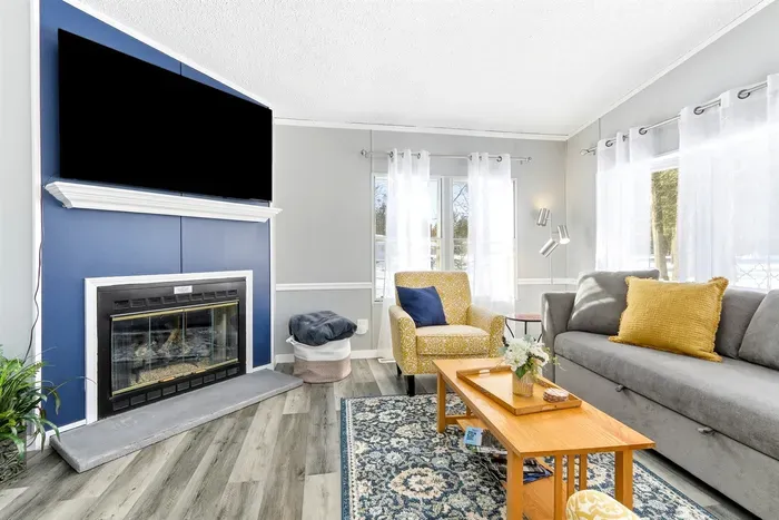 Cozy yet contemporary living area with colorful chairs, a blue fireplace, and a fully equipped kitchen.