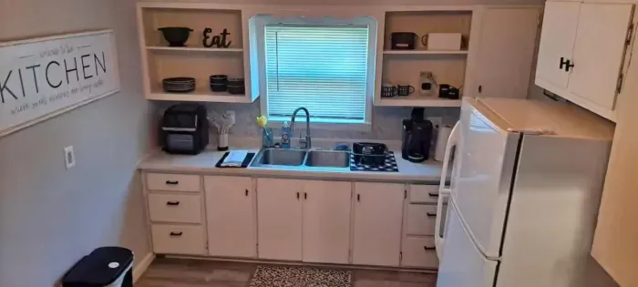 A modern kitchen equipped with high-end appliances and ample lighting. It has a coffee maker, oven, stove top, utensils, and all it takes to fix a delicious meal.