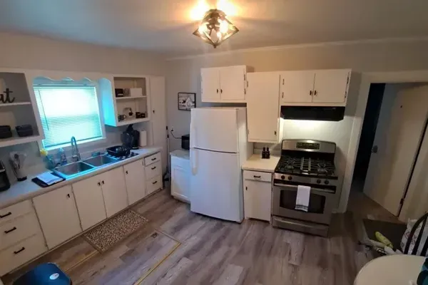 A modern kitchen equipped with high-end appliances and ample lighting. It has a coffee maker, oven, stove top, utensils, and all it takes to fix a delicious meal.