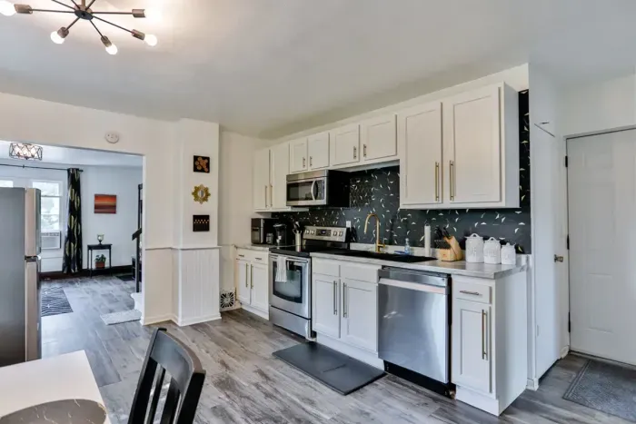 A modern kitchen equipped with high-end appliances and ample lighting. It has a coffee maker, oven, stove top, utensils, and all it takes to fix a delicious meal.