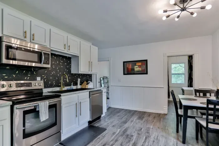 A modern kitchen equipped with high-end appliances and ample lighting. It has a coffee maker, oven, stove top, utensils, and all it takes to fix a delicious meal.