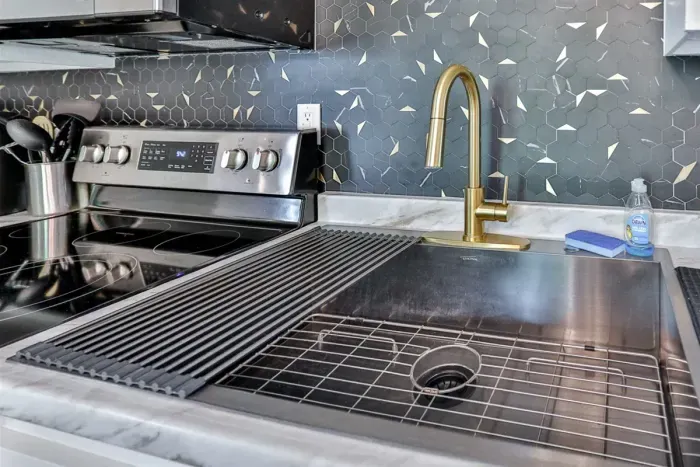 A modern kitchen equipped with high-end appliances and ample lighting. It has a coffee maker, oven, stove top, utensils, and all it takes to fix a delicious meal.