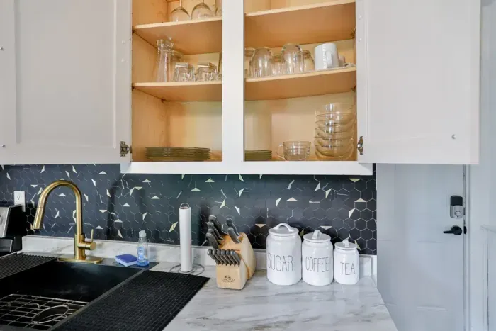 A modern kitchen equipped with high-end appliances and ample lighting. It has a coffee maker, oven, stove top, utensils, and all it takes to fix a delicious meal.