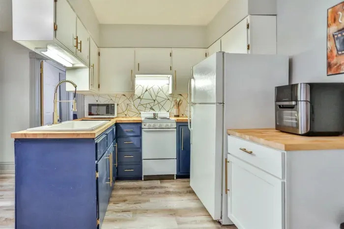 A modern kitchen equipped with high-end appliances and ample lighting. It has a coffee maker, oven, stove top, utensils, and all it takes to fix a delicious meal.