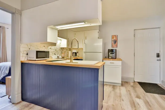 A modern kitchen equipped with high-end appliances and ample lighting. It has a coffee maker, oven, stove top, utensils, and all it takes to fix a delicious meal.