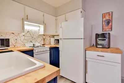 A modern kitchen equipped with high-end appliances and ample lighting. It has a coffee maker, oven, stove top, utensils, and all it takes to fix a delicious meal.