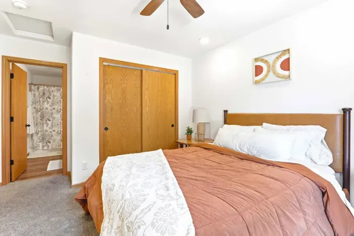 Relax into a calm, welcoming bedroom with cozy layers, warm wood accents, and convenient ensuite access.