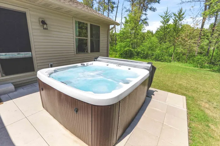 Soak, lounge, and unwind in a private backyard retreat surrounded by peaceful wooded views.
