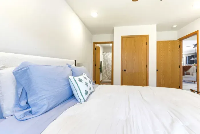 Sink into crisp, cozy bedding in a calm bedroom with easy ensuite access and a quiet connection to the main living space.