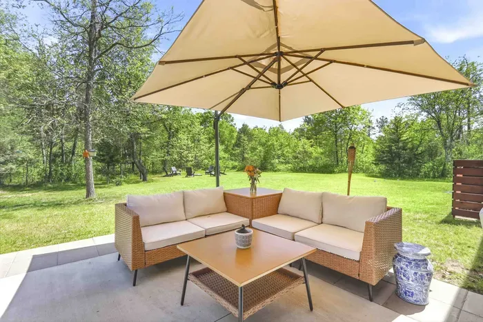 Settle into shaded patio comfort with cozy lounge seating, open green space, and peaceful wooded views made for slow afternoons.