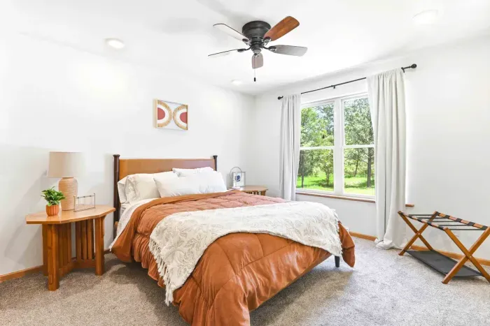 Wake up to soft natural light and peaceful treetop views in a warm, inviting bedroom designed for restful mornings.