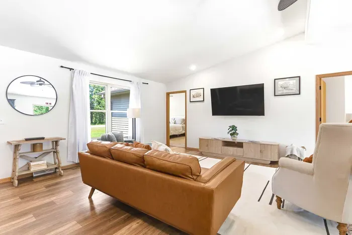 Unwind in a bright, airy living room with cozy seating, warm wood floors, and peaceful views just beyond the window.