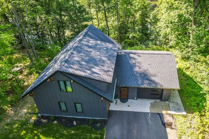 Arrive at a private wooded retreat with a spacious driveway and peaceful natural surroundings.
