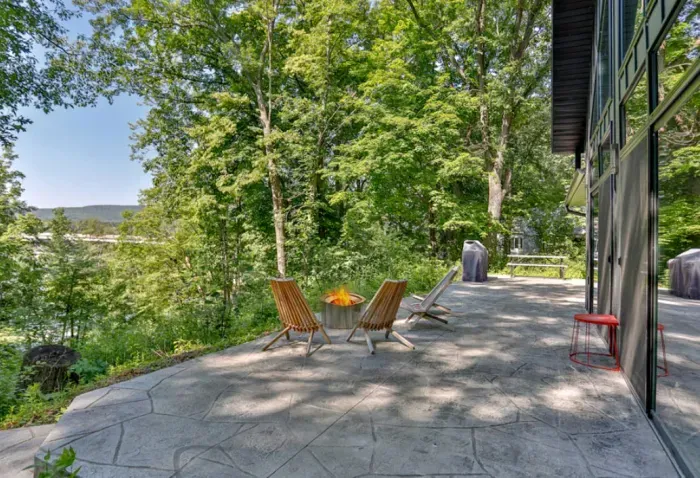 Gather around the outdoor fire pit with patio seating, surrounded by peaceful trees and scenic water views.