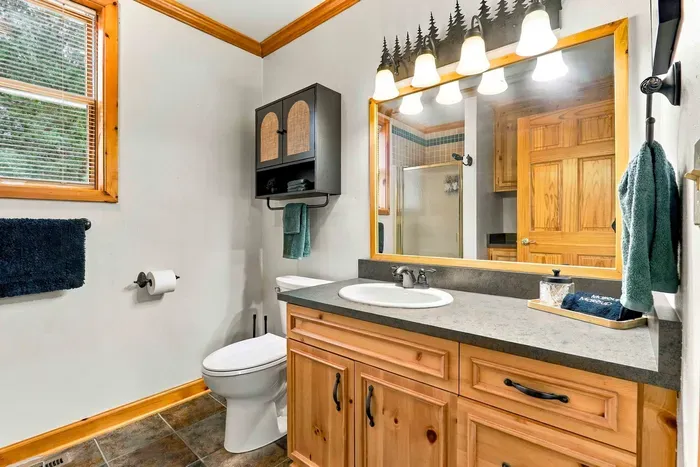 Refresh and unwind in this full bathroom featuring a spacious wood vanity, a large illuminated mirror, and a step-in glass-door shower.