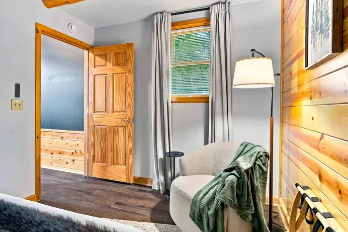 Unwind in this cozy reading corner featuring a plush accent chair, standing lamp, side table, and a convenient luggage rack for easy packing.