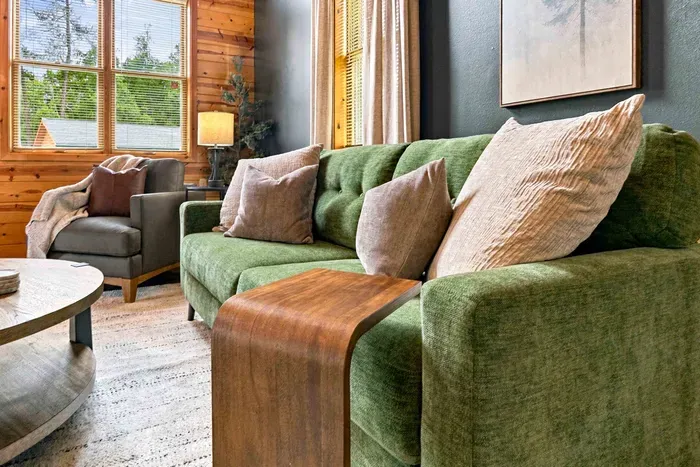 Relax in comfort with ample living room seating, featuring a stylish sofa and armchair arranged around a round wood coffee table.