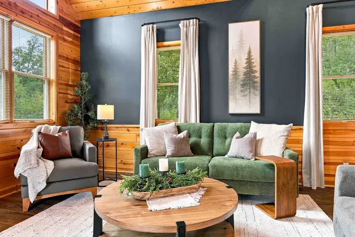 Relax after a day outdoors in this sunlit living area, anchored by a warm stone fireplace, soft plush seating, and high-beamed ceilings.
