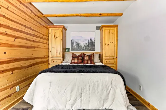 Retreat to this cozy bedroom featuring a plush queen bed, matching built-in nightstand wardrobes, and a comfortable armchair perfect for reading.