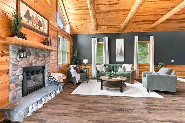 Unwind in this vaulted living room beside the classic stone fireplace, surrounded by plush armchairs and a cozy green sofa