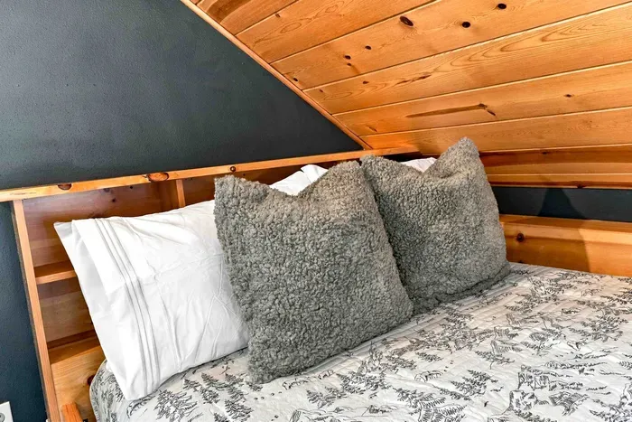 Relax in a cozy wooden loft outfitted with twin beds, built-in storage drawers, and a modern dresser.