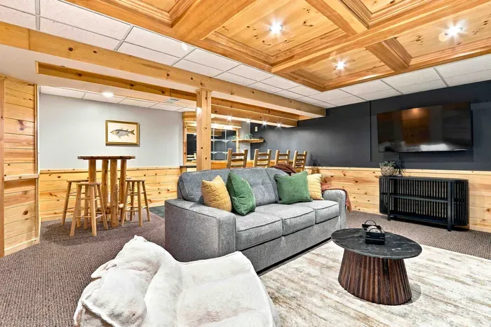 Host movie night or enjoy casual drinks in this inviting recreation space featuring a flat-screen TV, pub table with stools, and warm wood-paneled ceilings.