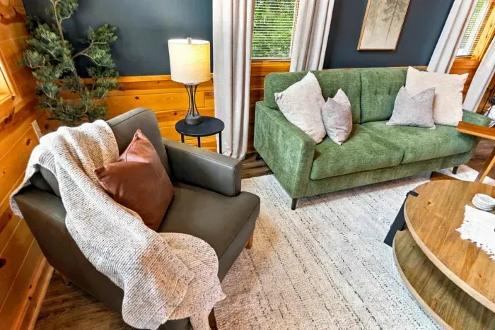 Enjoy quiet evenings in this warm, open-concept lounge, anchored by comfortable sofa seating, a large coffee table, and natural light from tall windows.