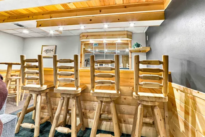 Gather for drinks or game night at the custom wet bar, complete with rustic log bar stools and warm ambient lighting.