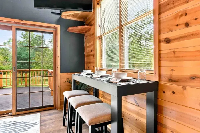 Savor meals with a view at this pub-style table with bar stools, perfectly set beside large windows and steps from the sliding glass door leading out to the deck.