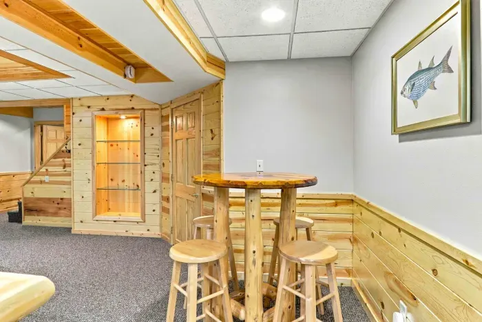Enjoy casual drinks or a game of cards at the rustic pub table with wooden barstools set within this cozy lower-level rec space.