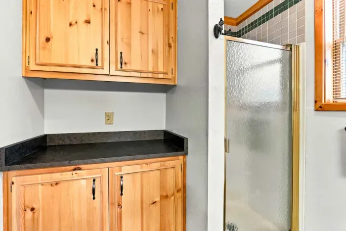 Refresh and unwind in this full bathroom featuring a spacious wood vanity, a large illuminated mirror, and a step-in glass-door shower.