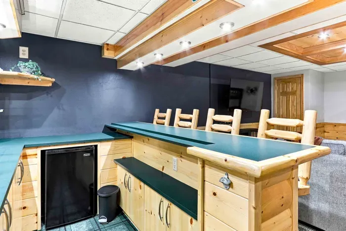 Mix drinks and store cold beverages with ease at the custom wet bar, complete with a mini fridge, built-in bottle opener, and rustic bar seating.
