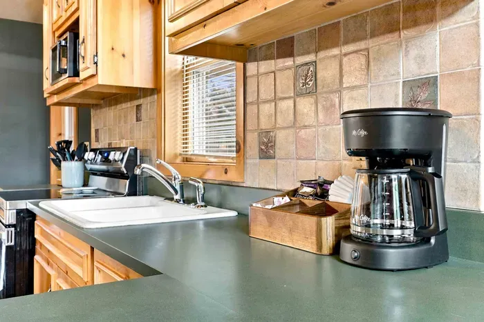 Start your morning right at this fully stocked coffee maker station, featuring a drip drip coffee maker and organizer box set right on the kitchen counter.
