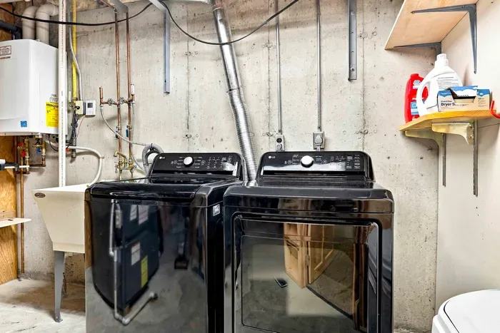 Enjoy the convenience of a dedicated laundry area equipped with a modern washing machine, dryer, and utility sink for an effortless stay.