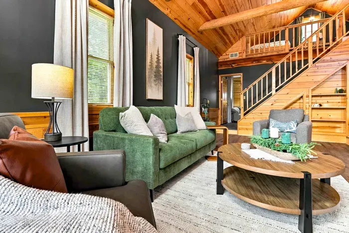 Gather in this inviting living area featuring a plush green sofa, comfortable armchairs, and a round coffee table beneath vaulted wood ceilings.
