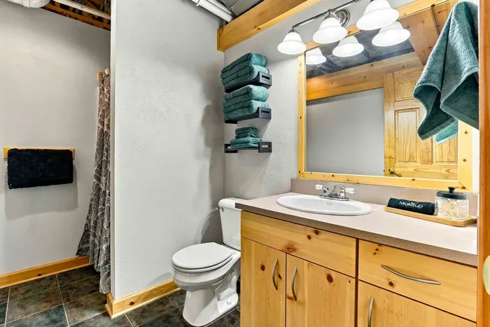 Refresh in this well-appointed bathroom featuring a wooden vanity with mirror, a walk-in shower, and plenty of soft, fresh towels ready for your stay.