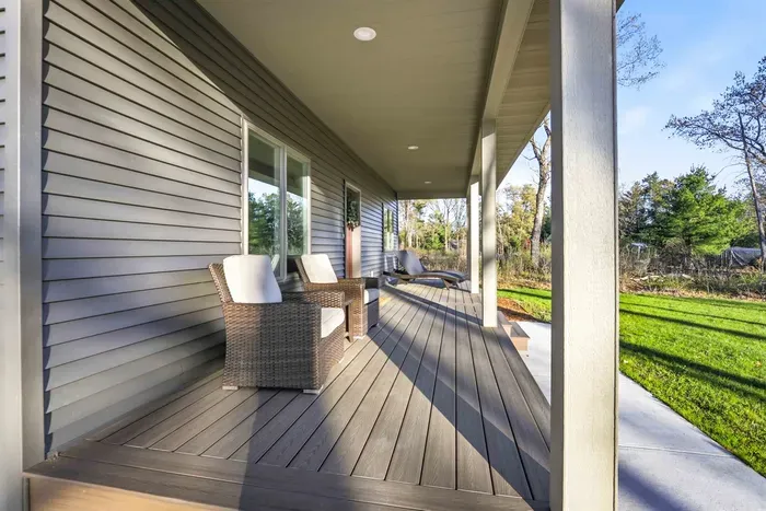 Covered front porch with comfortable seating, modern decking, and a peaceful view of the surrounding green space.