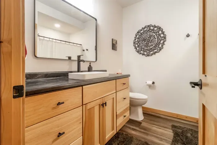A clean, functional bathroom featuring a vanity mirror with a cabinet below, offering both style and convenient storage.