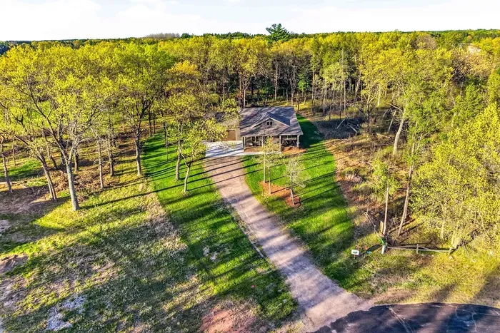 Scenic aerial view showcasing the home’s secluded feel, expansive green space, and beautiful surrounding woodland.