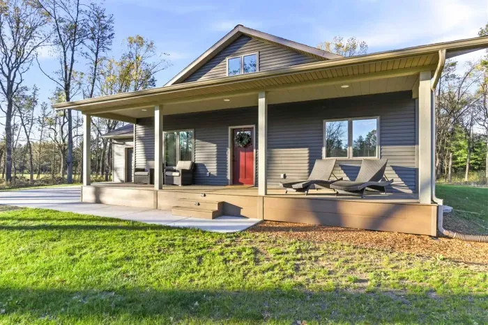 Serene bunkhouse setting with a long driveway approach, mature woods, and a relaxed countryside feel.