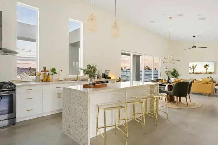 ✨ Where design meets gathering. Enjoy coffee or cocktails at the marble-style island with brass accents—this modern desert home was built for conversation and togetherness.