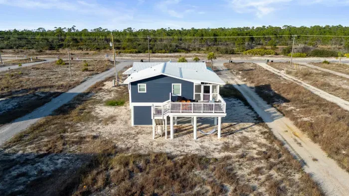 The back of Blissful Shores, opening to a spacious yard, perfect for relaxing after a beach day and soaking in the coastal breeze.