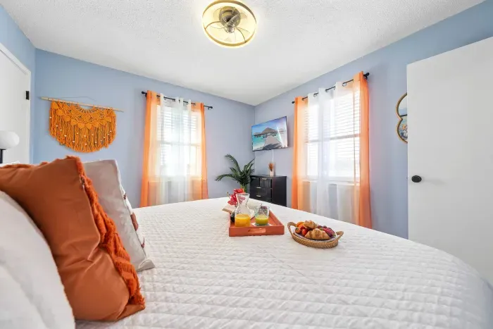 First Guest Bedroom: A king-size bed surrounded by soft orange hues, echoing the glow of a Gulf Coast sunrise.
