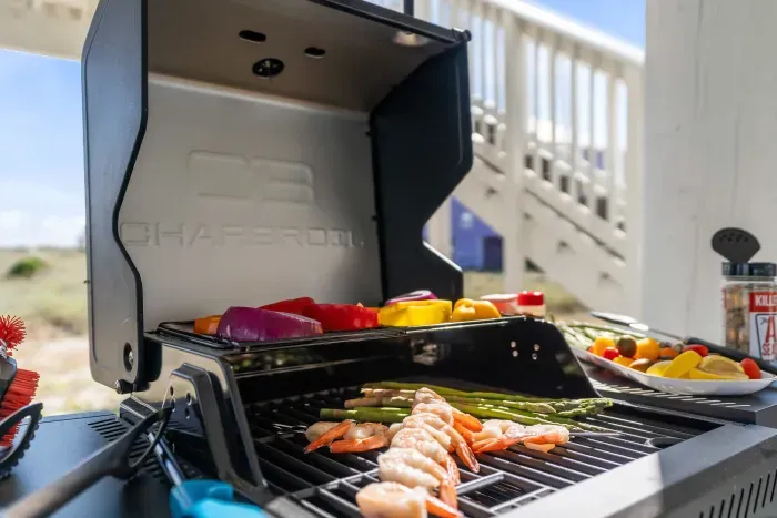 Under the house, the grill is fired up with Gulf Coast shrimp — a shaded spot where sandy toes and good food come together.