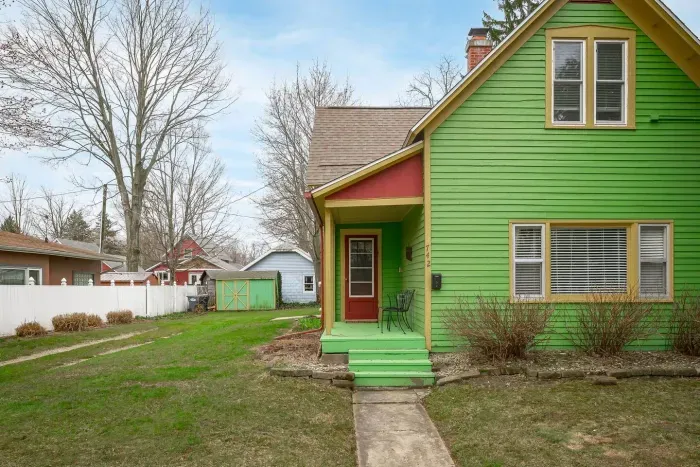 Charming Exterior: Bright green facade with inviting porch, perfect for soaking up the sun!