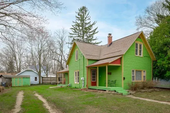 Exterior: Vibrant green retreat with inviting porch and lush yard, perfect for outdoor fun!