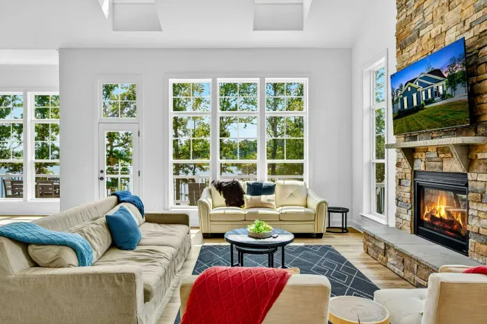 Great Room - Soaring ceilings, a floor-to-ceiling stone fireplace, and walls of windows fill this living space with natural light and lake views.